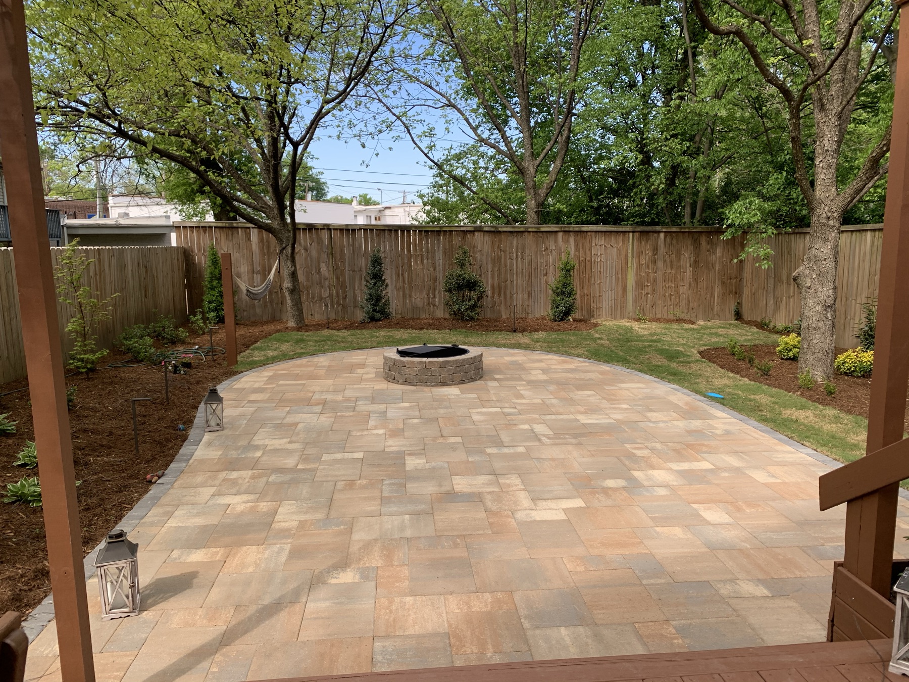 After: Paver patio with a round fire pit and new planting beds in a Charlotte backyard