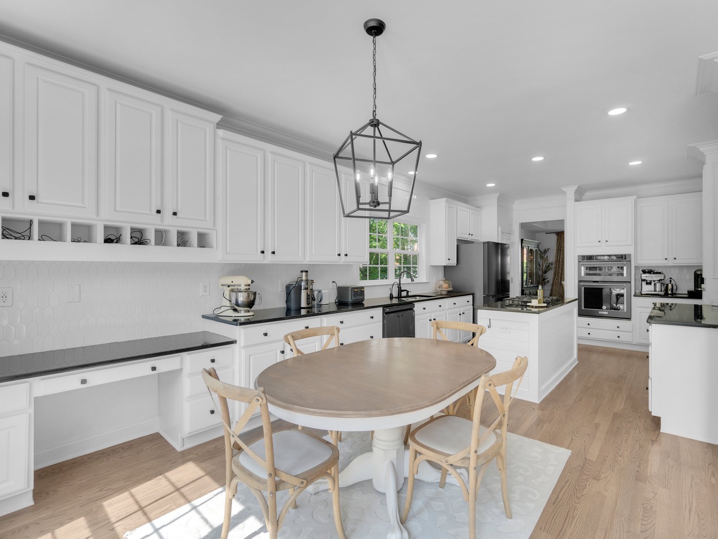 White remodeled kitchen with a lantern pendant, built-in desk and oval dining table